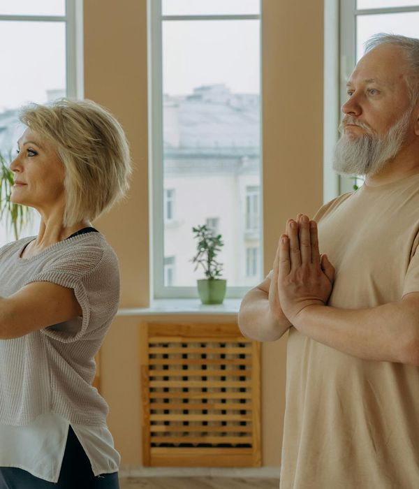 Elderly woman calmly practicing yoga indoors, focus and serenity.